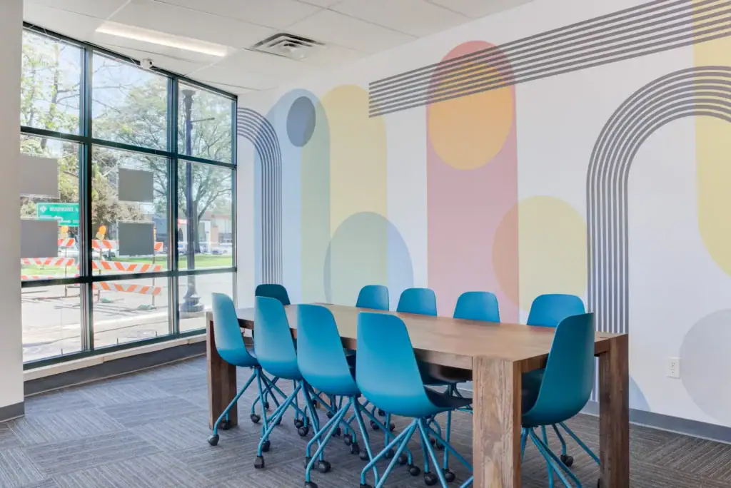 Meeting room with blue chairs, wooden table, and colorful geometric wall art