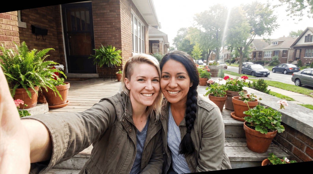 A couple taking a selfie on the steps of a brick Redford bungalow
