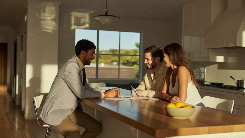 Real estate agent reviewing buyer's agent fees with a couple at a kitchen island